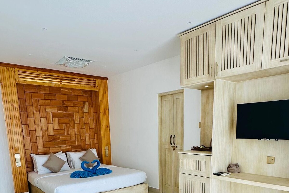A modern bedroom with a bed, a sofa, a TV, and built-in cabinets.