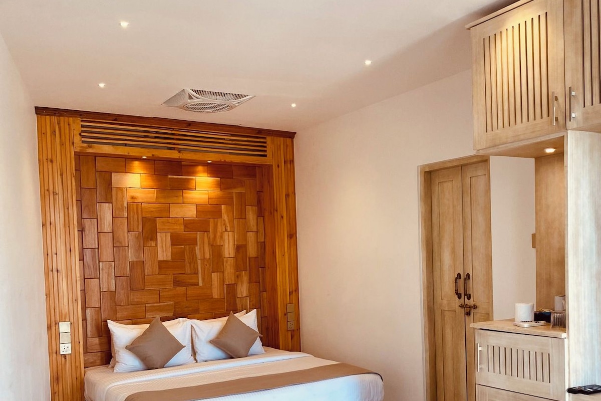 A bedroom with a bed, wooden headboard, wardrobe, and a ceiling fan.