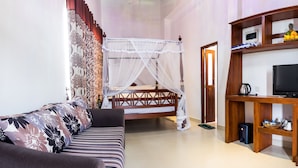 Un dormitorio con una cama, televisión, refrigerador y estante de madera con diversos objetos.