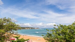Una playa con cielos despejados, una orilla arenosa y algo de vegetación.