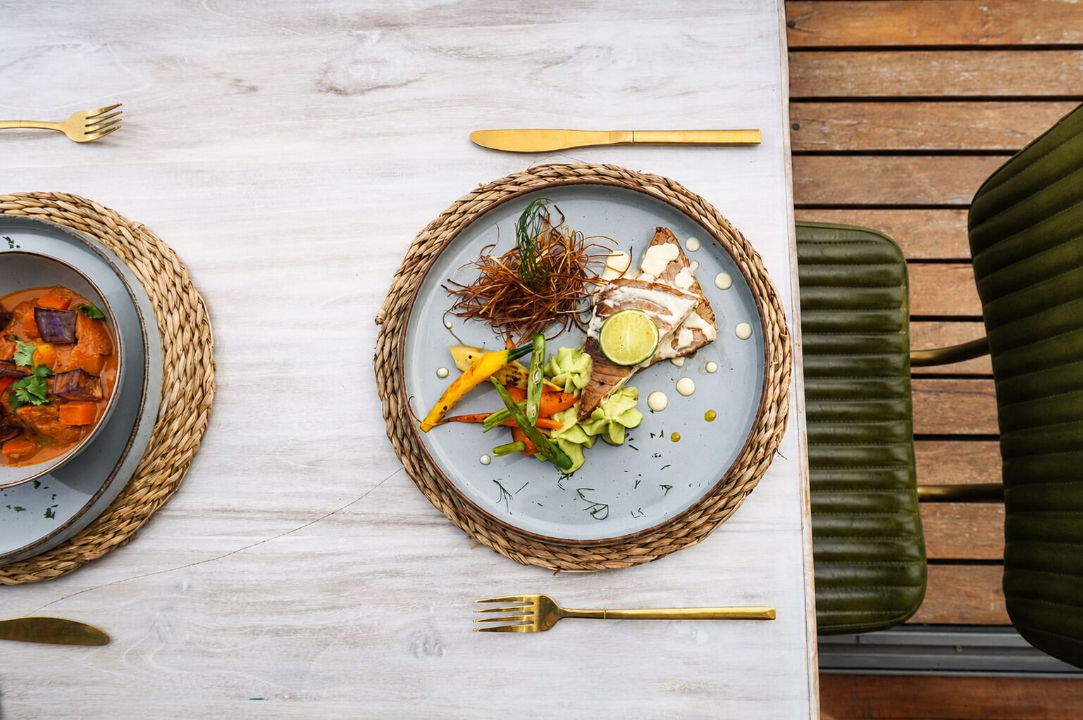 A dining table with two plates of food, a fork, and a knife.