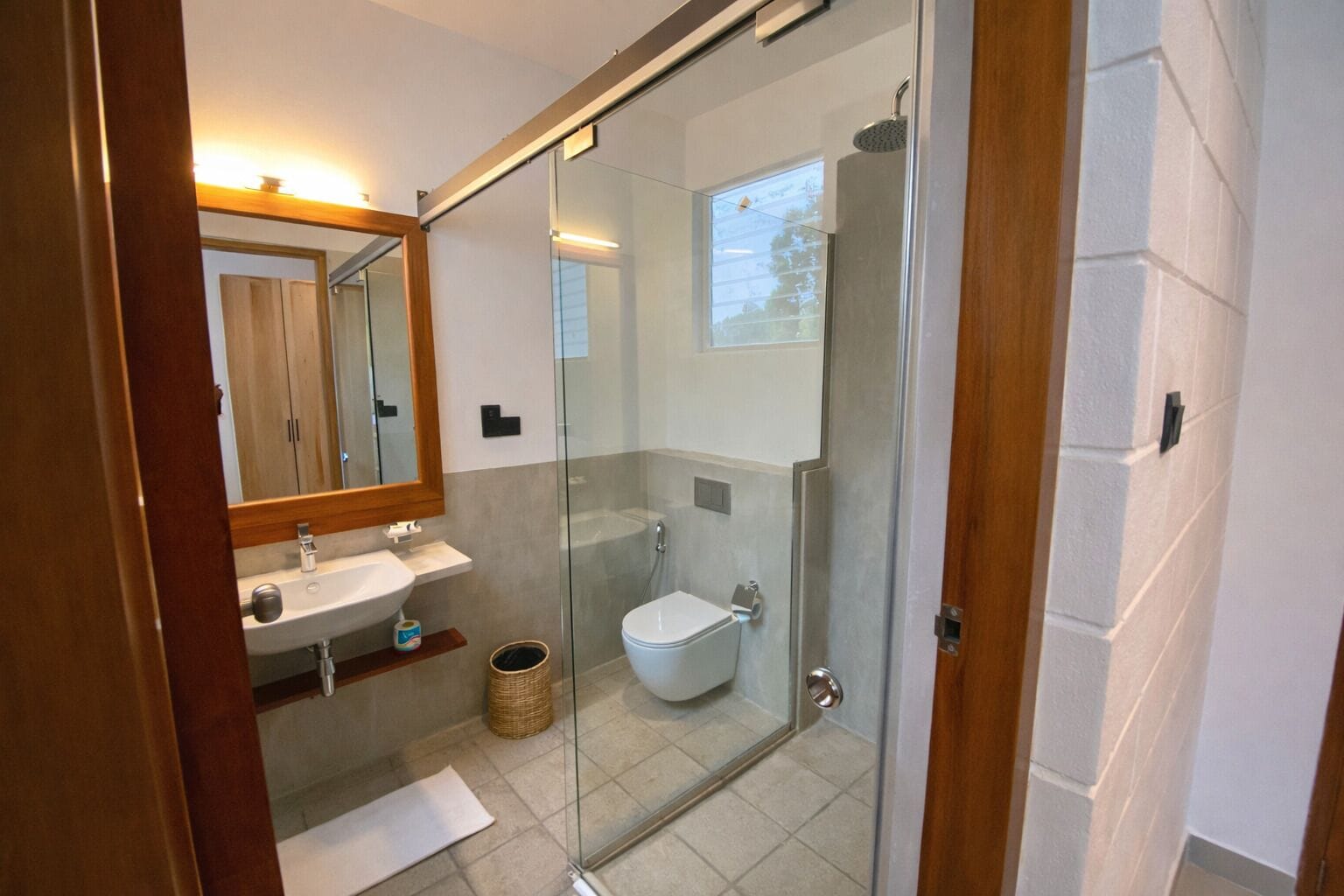A modern bathroom with a glass shower enclosure, a sink, and a toilet.