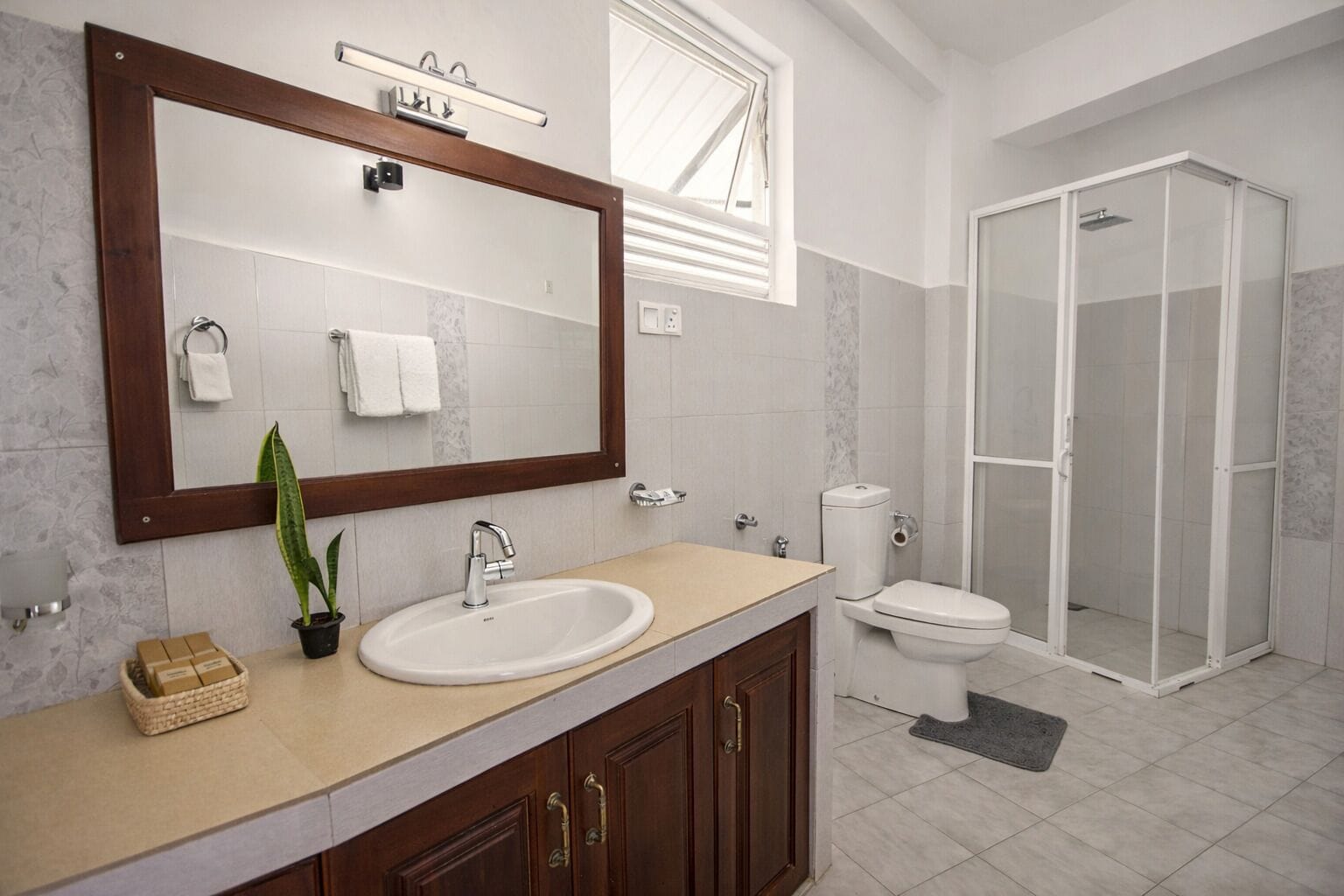 A bathroom with a large mirror, a sink, a toilet, and a shower area.