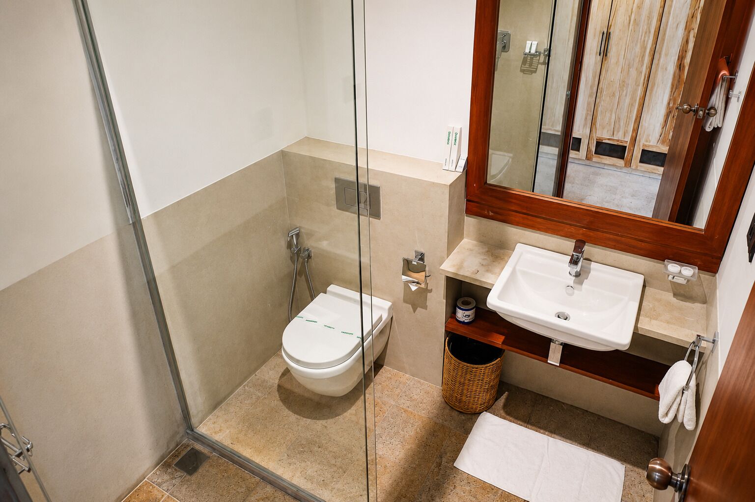 Ein Badezimmer mit Duschkabine aus Glas, einer weißen Toilette, einem Waschbecken mit Spiegel darüber und einem Handtuchhalter.