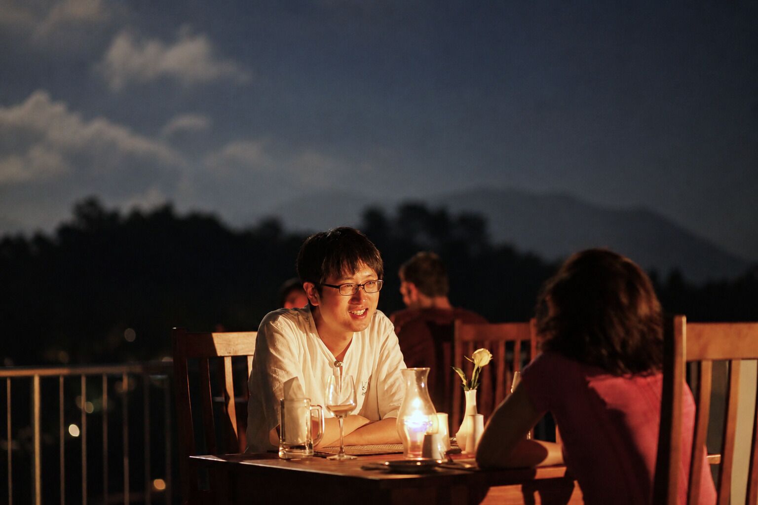A dining table with chairs, a candle, and a glass of water.