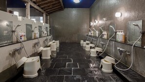 A public restroom with multiple urinals and sinks, tiled walls, and a wooden ceiling.