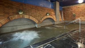 A spa area with a brick wall, tiled floor, and a water feature.