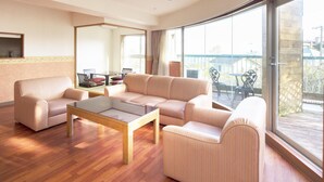 A spacious living room with a sofa set, a coffee table, and a dining area with chairs and a table.