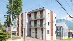 En modern, flervåningsbyggnad med ett platt tak, en balkong på andra våningen och en skylt som visar att det är en bostadsbyggnad.