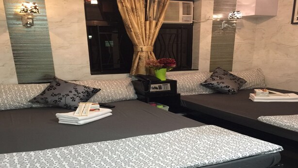 A modern hotel room with a sofa bed, a small table with a vase of flowers, and a window with curtains. - Hi-Inn (Kowloon)
