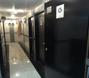 Un pasillo con puertas negras, cada una señalizada con un cartel de puerta contra incendios y un símbolo de accesibilidad para sillas de ruedas.
