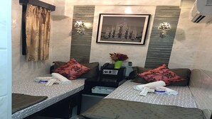 A compact hotel room with two single beds, a small table with a telephone, a vase with flowers, and a framed picture on the wall. - Hi-Inn (Kowloon)