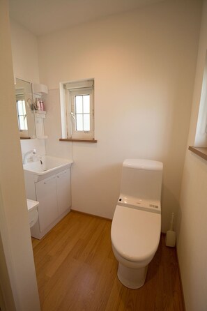 A small, clean bathroom with a toilet, sink, and mirror.