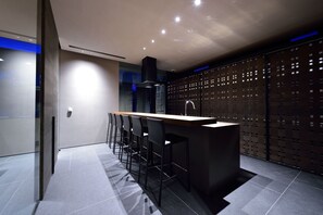 A modern kitchen with a bar area, bar stools, and a decorative wall with a pattern. - Holiday Niseko Ori (Kutchan)