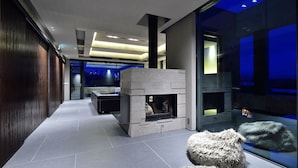 A modern interior with a stone fireplace, glass walls, and a minimalist design.