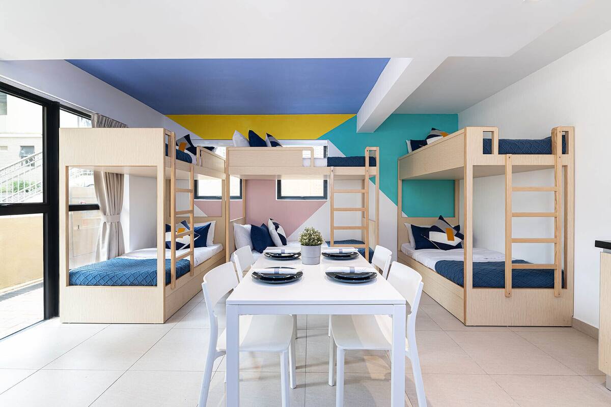 Ein Kinderzimmer mit Etagenbetten, einem weißen Tisch und Stühlen.