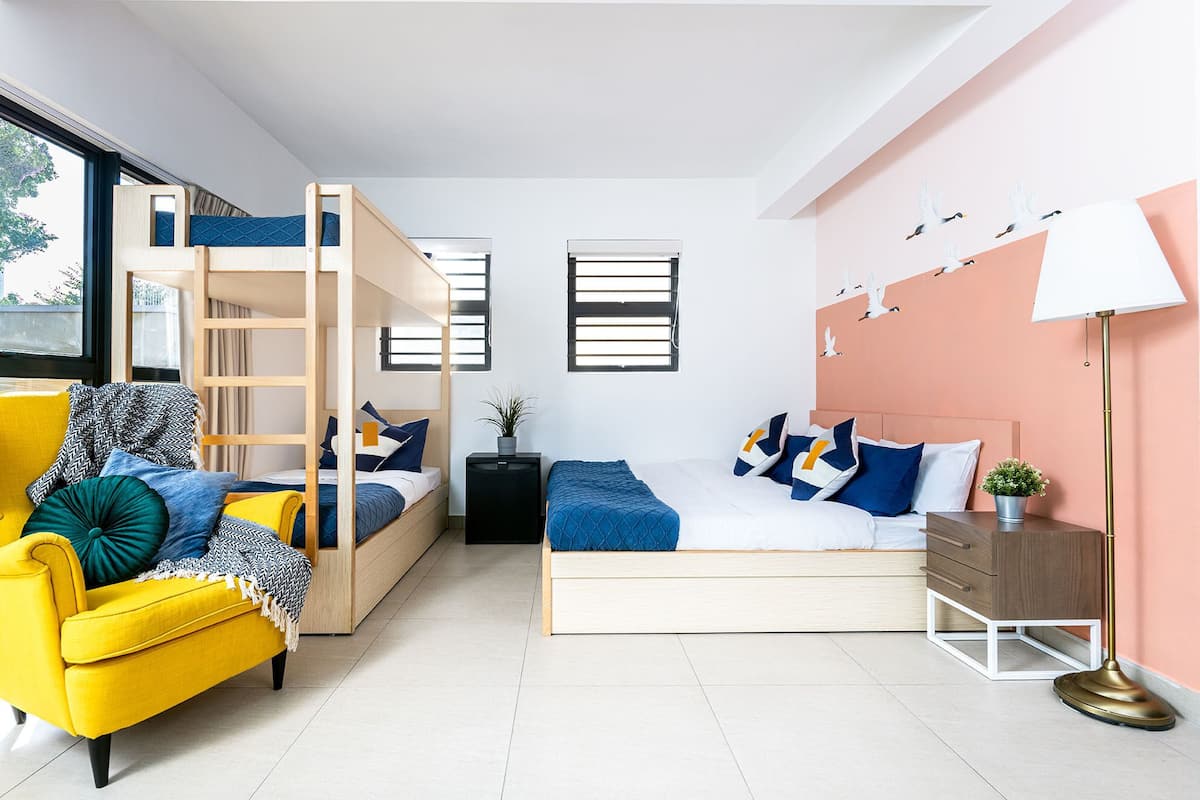 Ein modernes Schlafzimmer mit Etagenbett, einer Schlafcouch, einem Nachttisch, einer Lampe und einer Wand mit Vogelaufkleber.