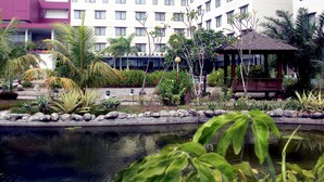 Un patio de hotel con un estanque, palmeras y un pabellón.