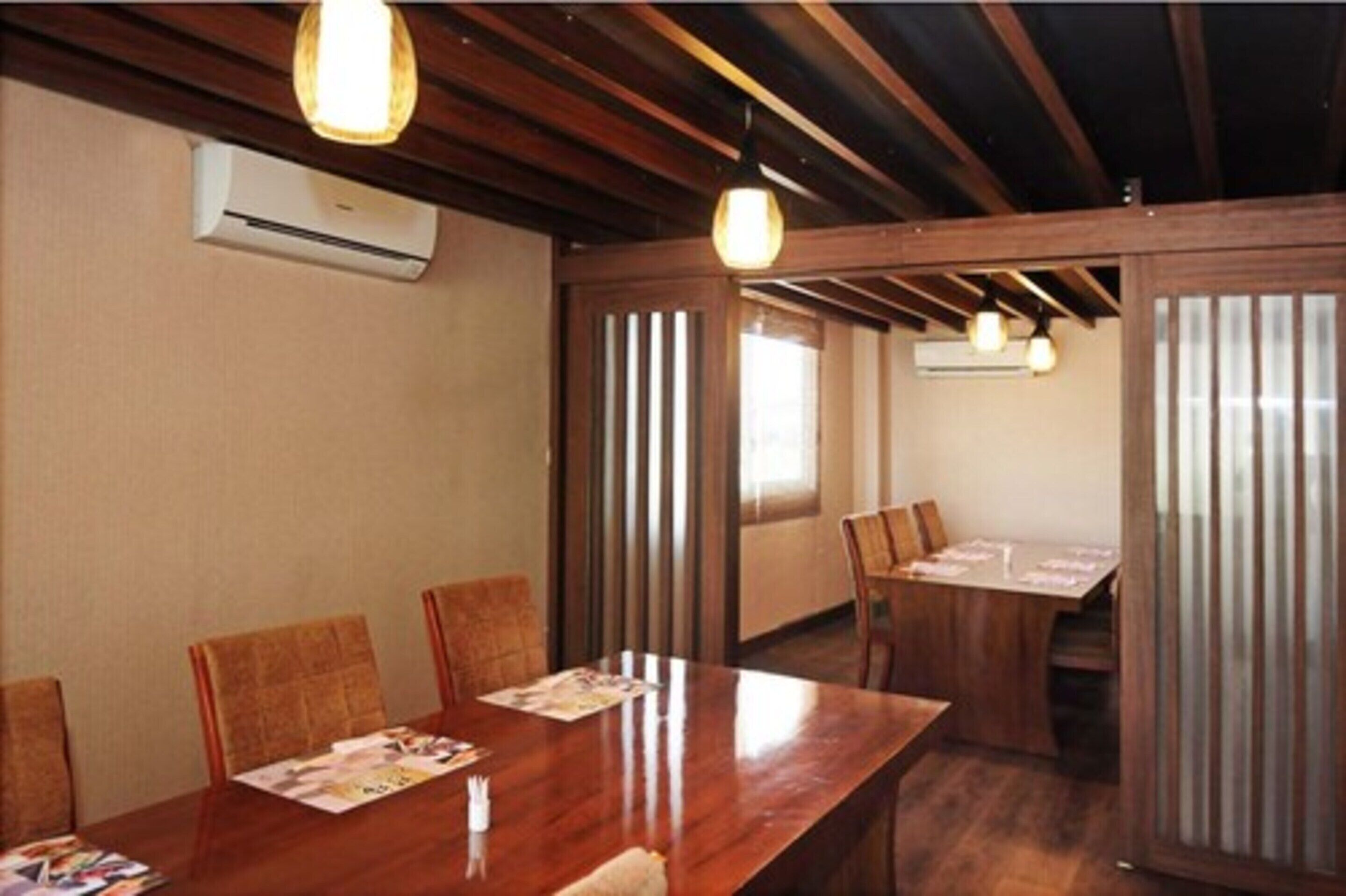 A conference room with wooden tables and chairs, a ceiling fan, and an air conditioning unit.