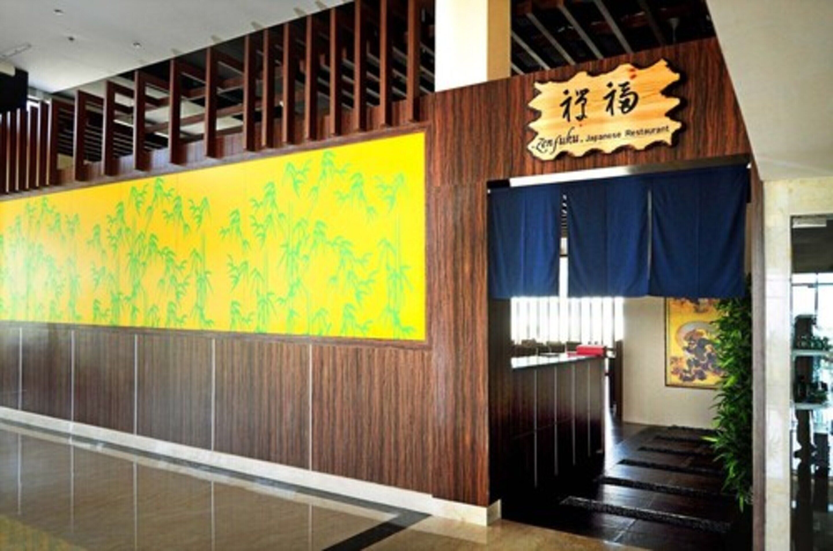 A modern interior with a large yellow wall mural, a wooden panel design, and a sign for Zenjiu Japanese Restaurant.