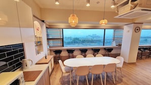 Une cuisine moderne avec une grande table à manger, des chaises noires et une vue sur la ville par la fenêtre.