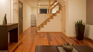 A modern interior with a wooden staircase, a kitchen area, and a dining space. - Holiday Niseko Shinsetsu Apartments (Kutchan)