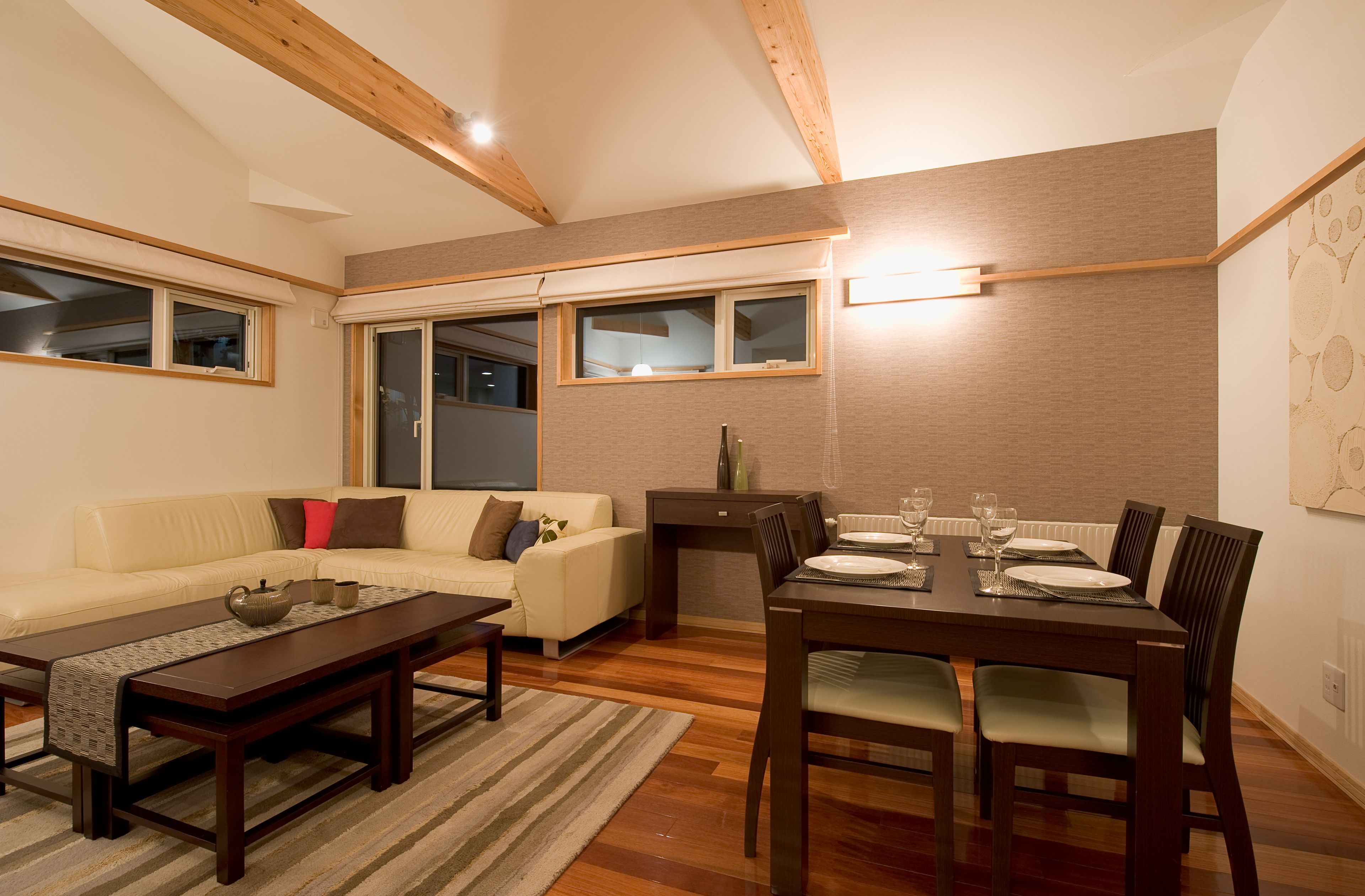 A living room with a sofa, coffee table, and dining table set for four.
