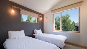 A bedroom with two beds, a large window, and a view of trees. - Holiday Niseko Shinsetsu Apartments (Kutchan)