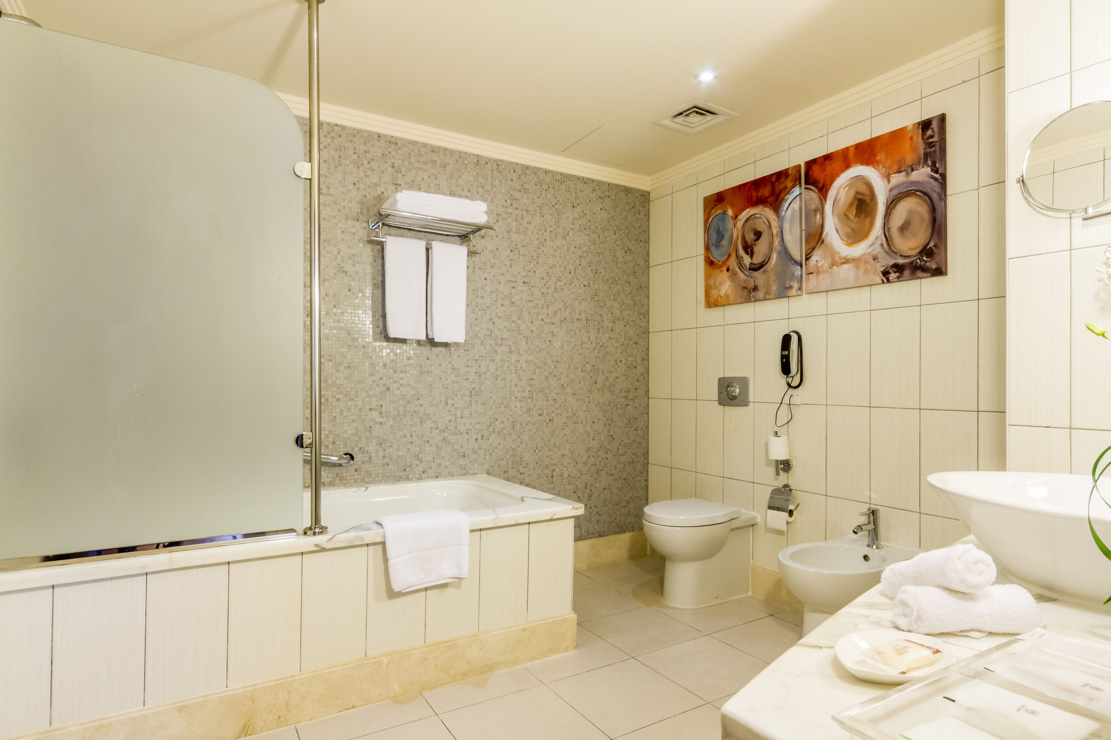 A modern bathroom with a bathtub, toilet, bidet, and sink.