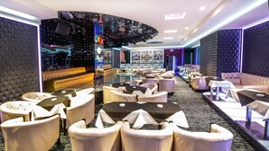 Een moderne lounge met zachte fauteuils, een glazen scheidingswand en sfeerverlichting.