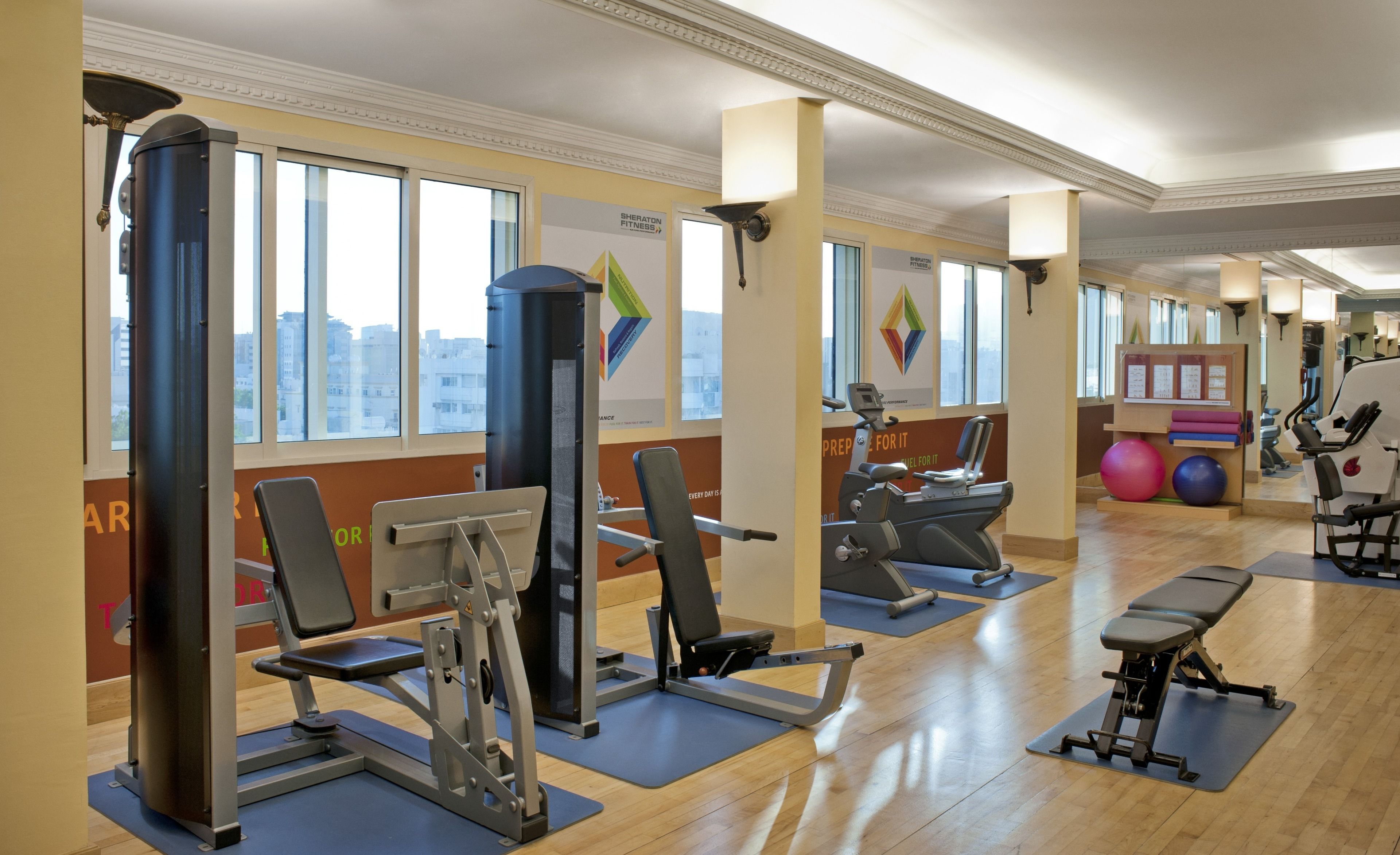 A gym with various exercise equipment, large windows, and a view of the city.