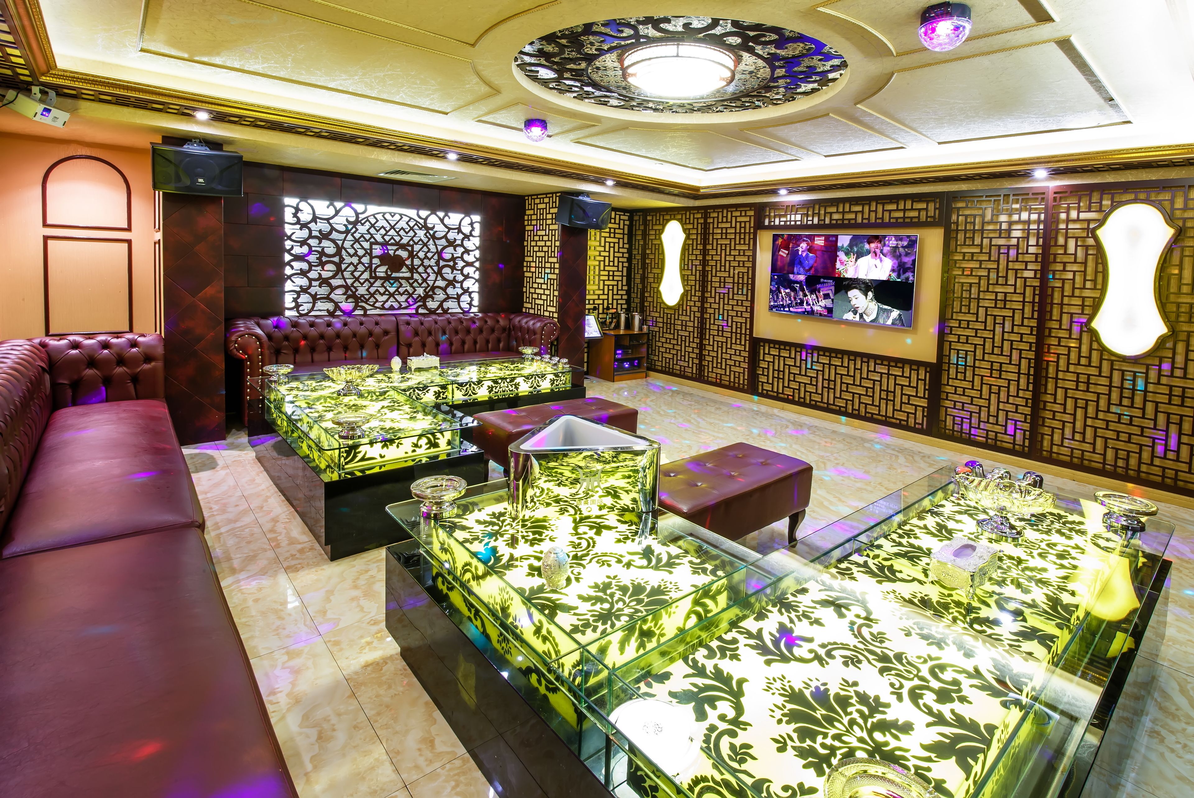A luxurious lounge area with plush seating, a glass coffee table, and a decorative wall with a television.