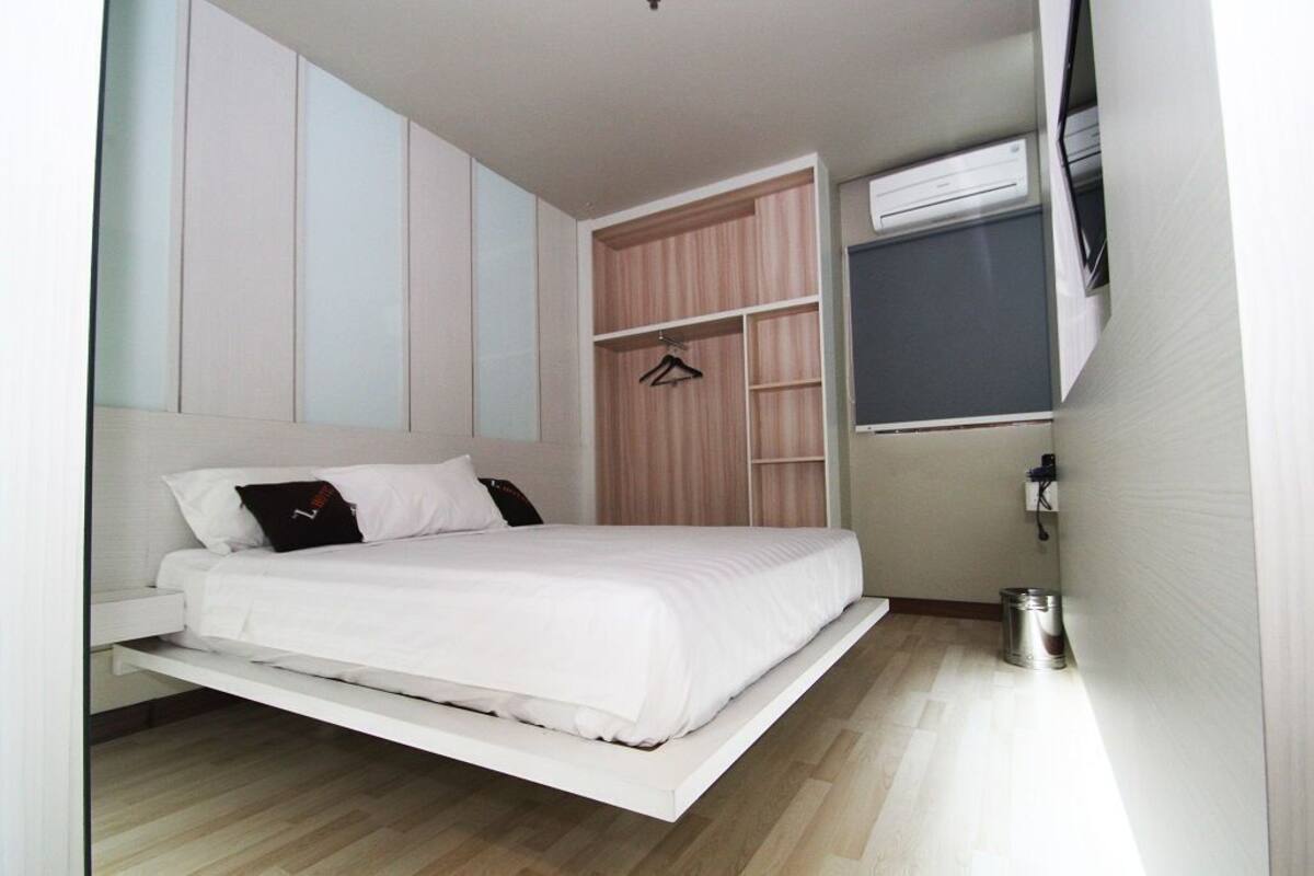 A modern bedroom with a bed, built-in wardrobe, and a window.