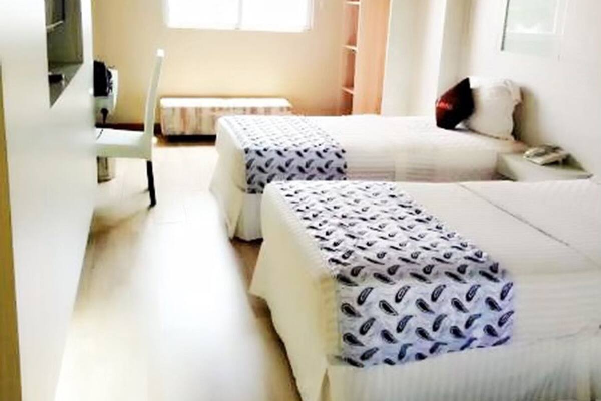 A room with two beds, a desk, a chair, and a wardrobe.