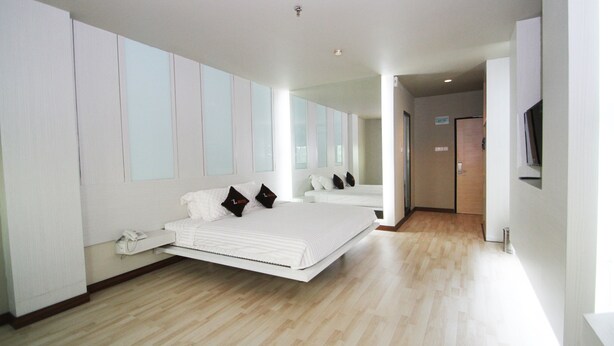 A modern hotel room with a large bed, a bedside telephone, and a television on the wall. - The L Hotel Entertainment (Batam)