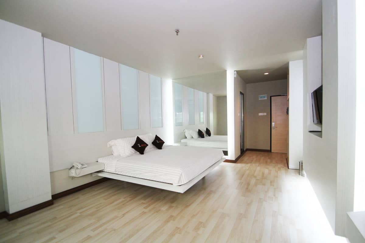 A modern hotel room with a large bed, a bedside telephone, and a television on the wall.