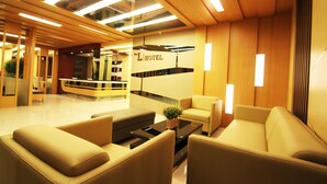 A modern hotel lobby with a reception desk, sofas, and a coffee table. - The L Hotel Entertainment (Batam)