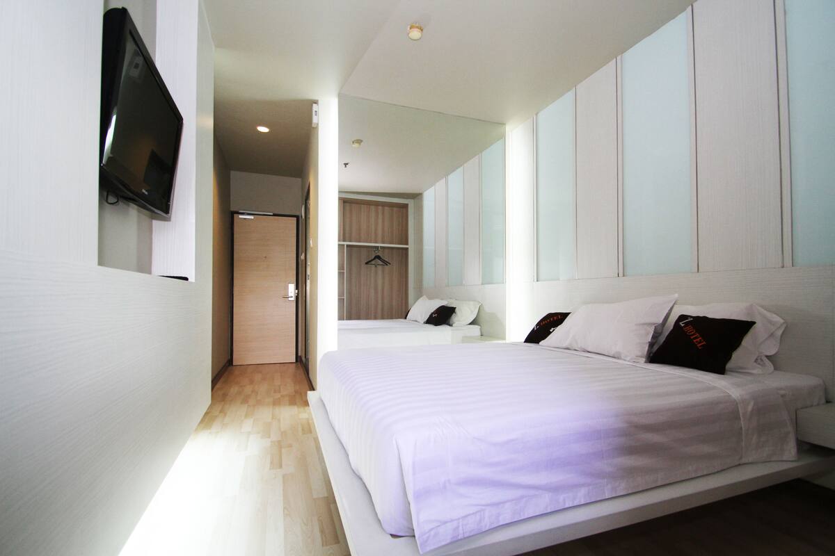 A modern hotel room with a large bed, a television mounted on the wall, and a walk-in closet.