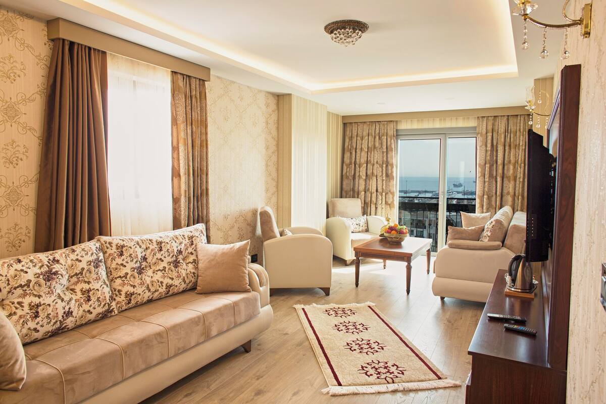 A spacious living room with a sofa, armchairs, a coffee table, and a TV stand.