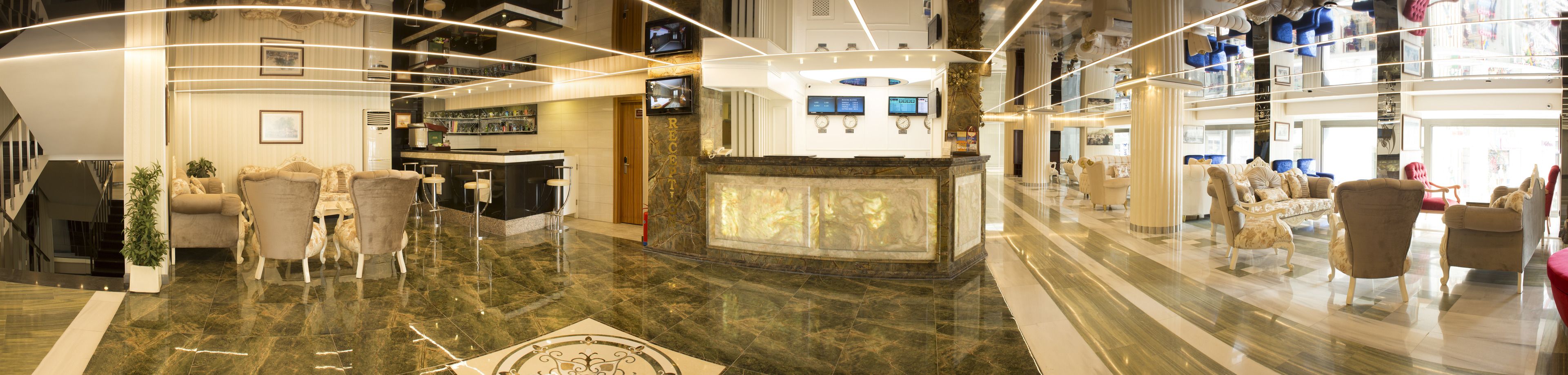 Una hall d'albergo con reception, area salotto e una scala.