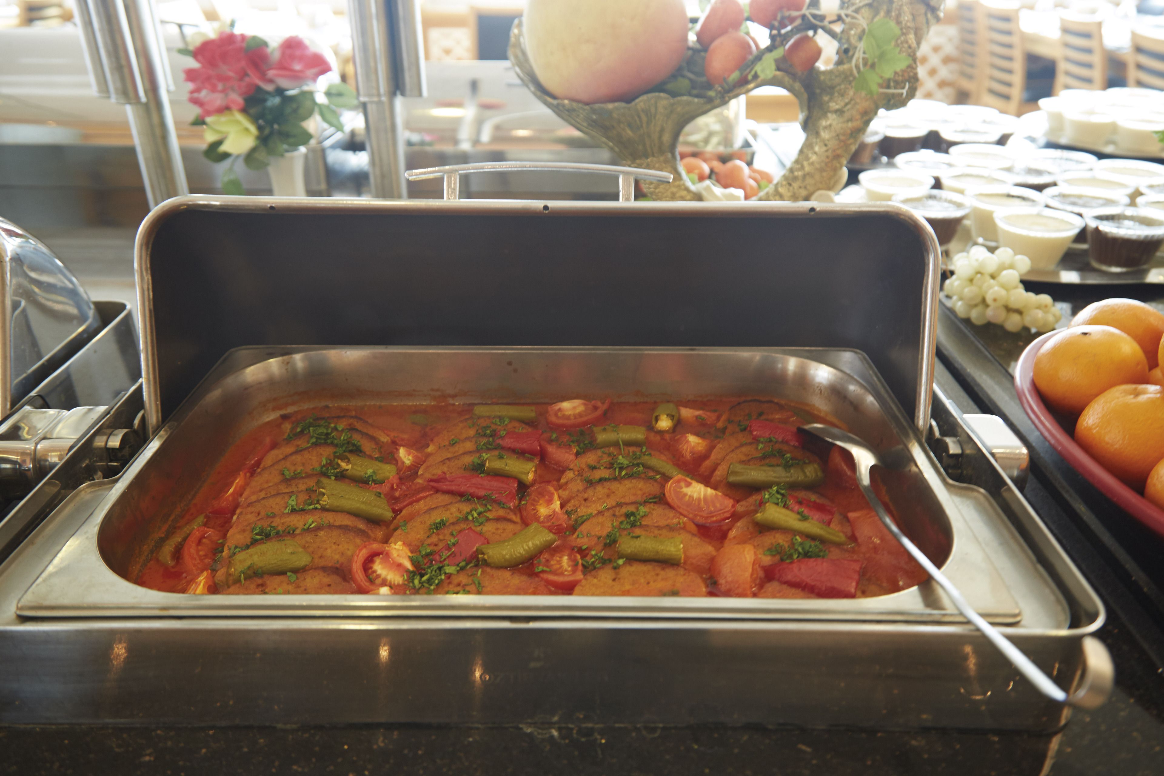 A buffet with a variety of dishes including a vegetable casserole and a selection of fruits.