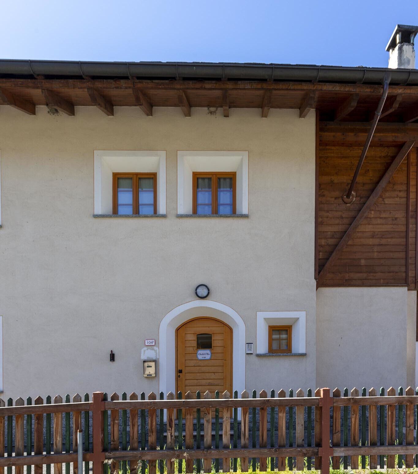 A building with a wooden facade, a central arched entrance, and two small windows above the door.