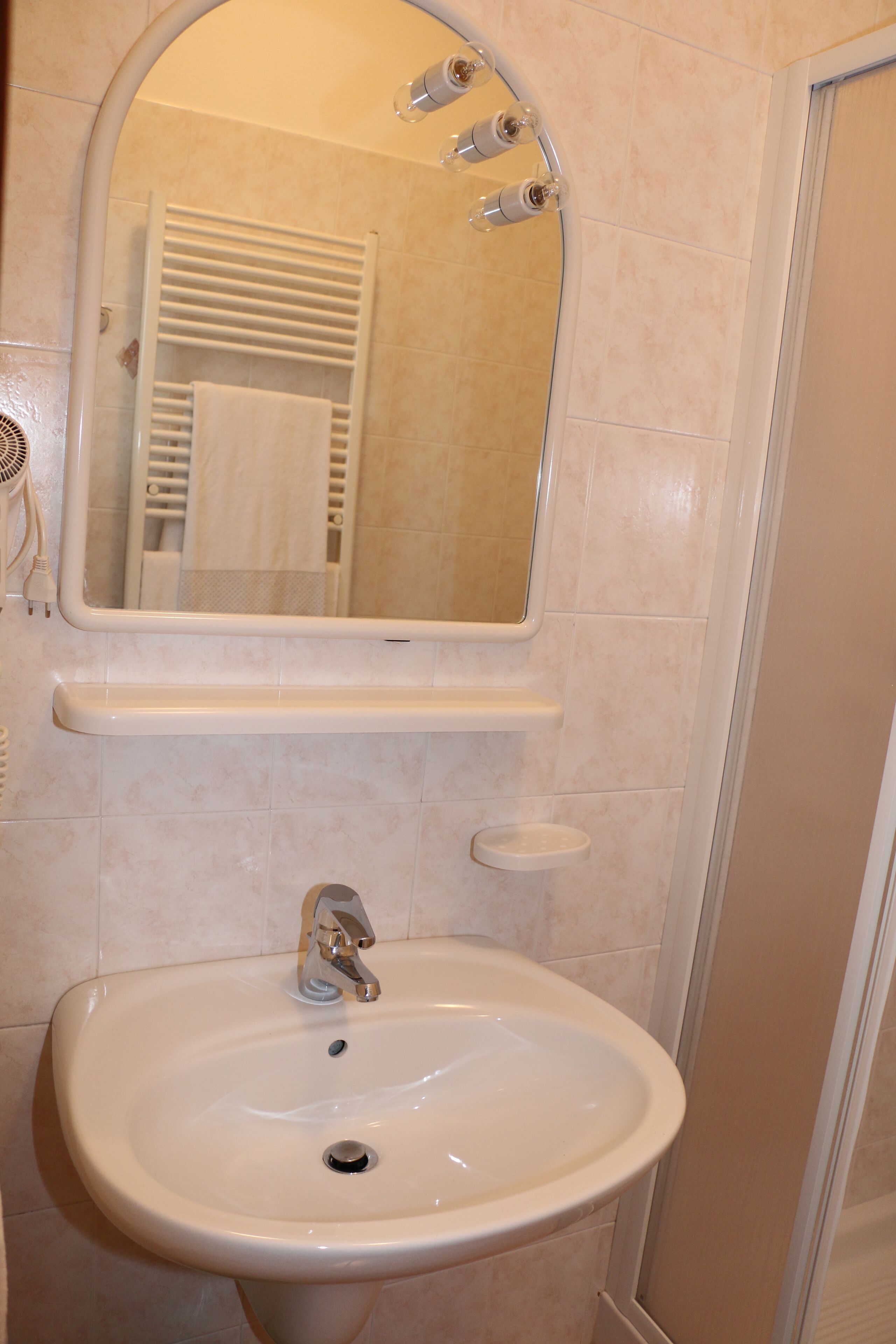 A bathroom with a sink, mirror, and towel rack.