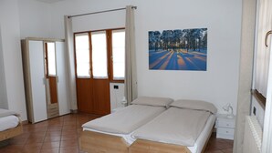 Une chambre à coucher avec un lit en bois, une table de chevet, un radiateur et une porte donnant sur une autre pièce.