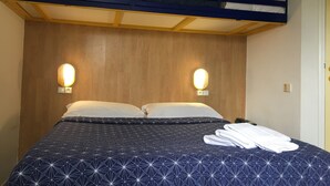 A bunk bed with a wooden headboard, two bedside lamps, and a neatly made bed with a geometric-patterned duvet. - Hotel Noctuel - Blois (Saint-Gervais-la-Foret)