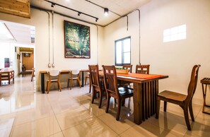 Un comedor amplio con mesas y sillas de madera, un cartel grande en la pared y un ventanal que proporciona luz natural.
