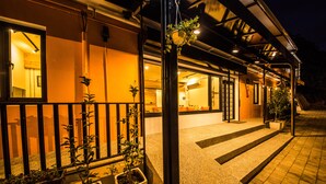 A hotel entrance with a gated driveway, potted plants, and a well-lit interior visible through the windows. - JNbnb (Beinan)