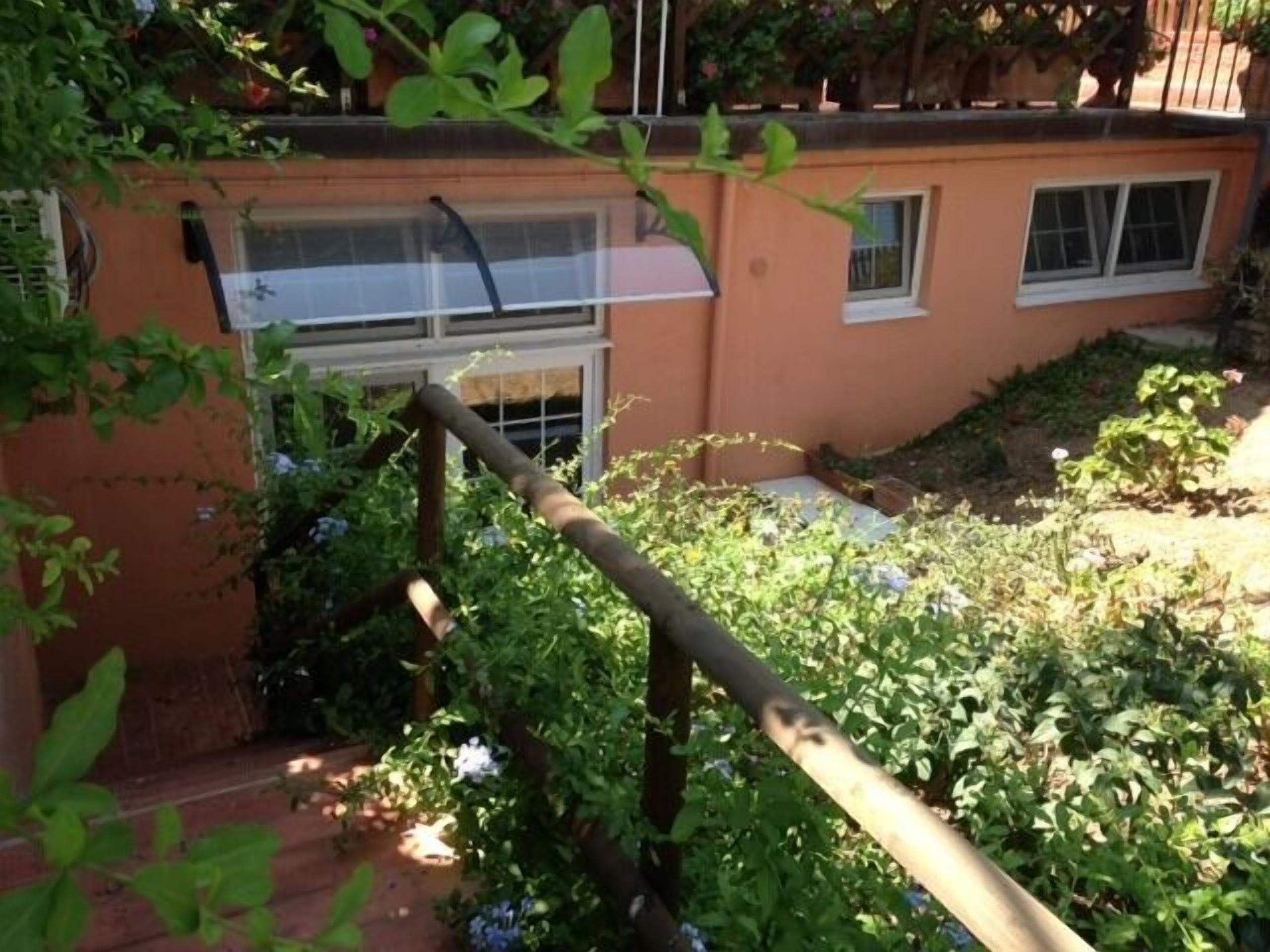 Un jardín con valla de madera, una ventana y diversas plantas.