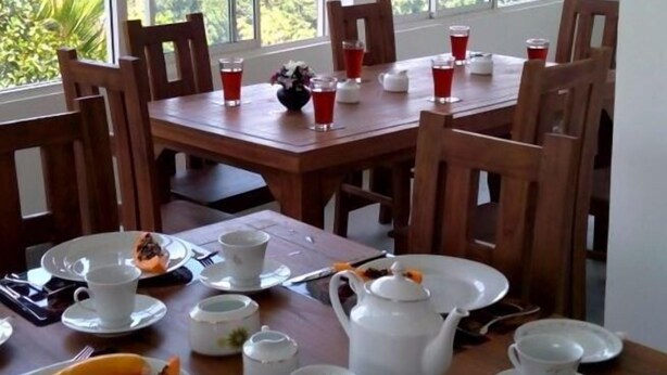 Un'area pranzo con un tavolo apparecchiato per la colazione, con piatti, tazze e un bollitore.