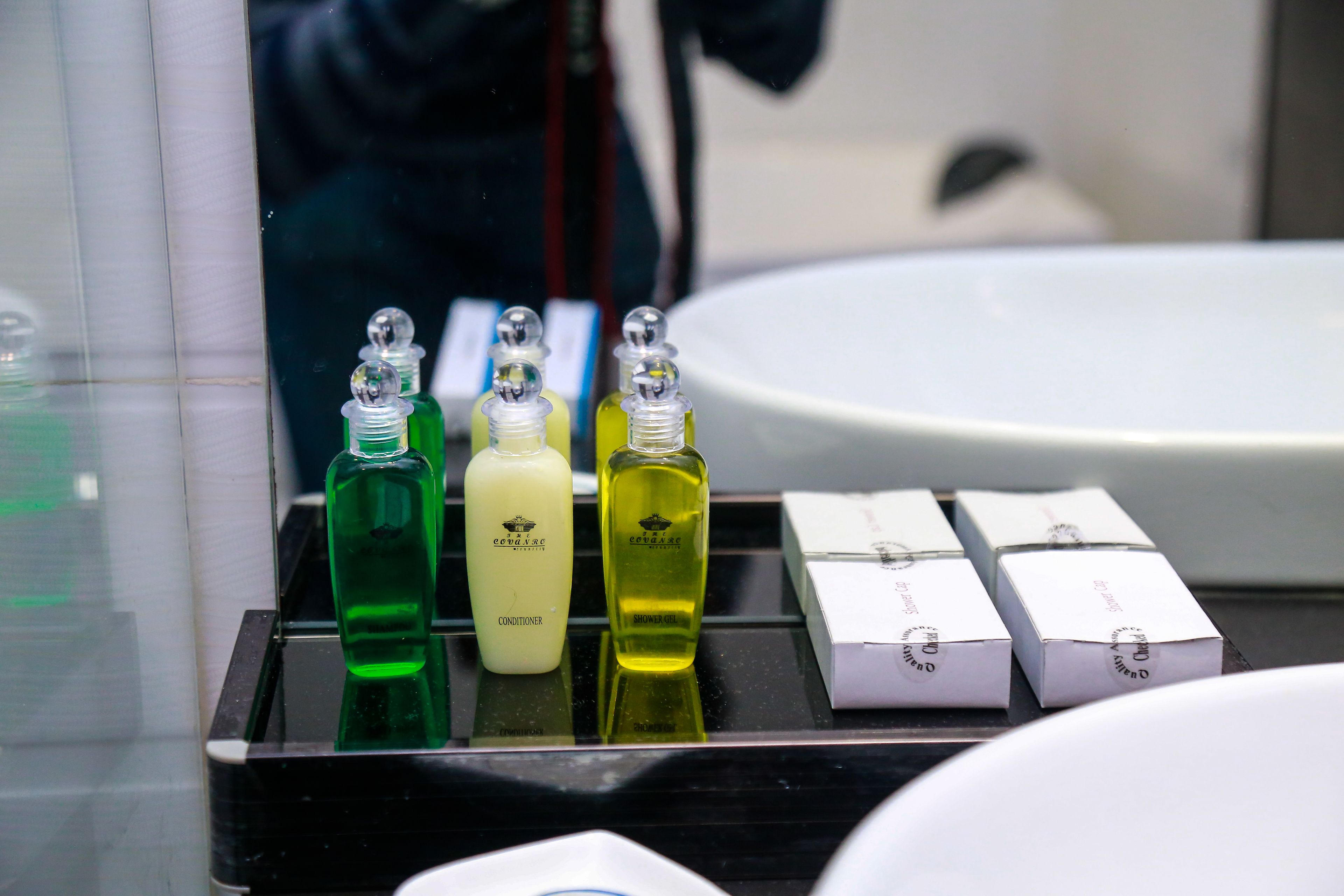 A bathroom counter with three bottles of liquid soap and several boxes of toiletries.